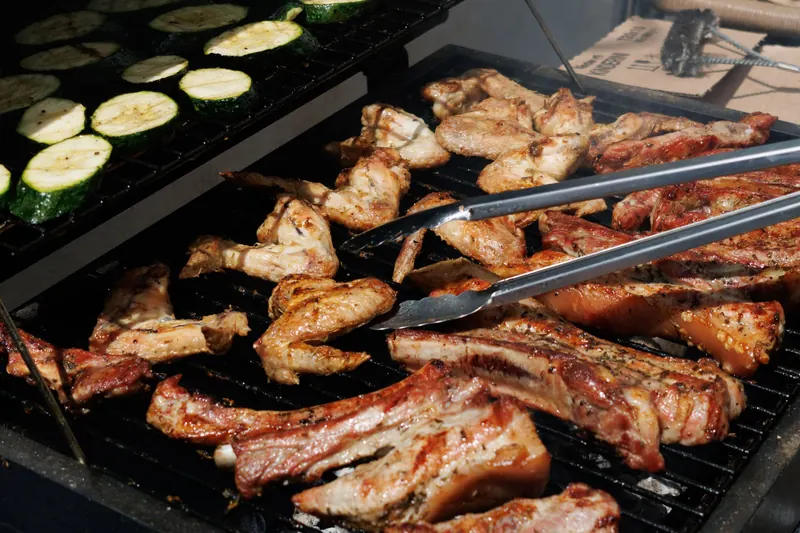 Delicious barbecue chicken and zucchini grilling outdoors on a sunny day