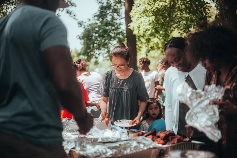 A lively barbecue gathering with diverse group outdoors enjoying food and summer weather