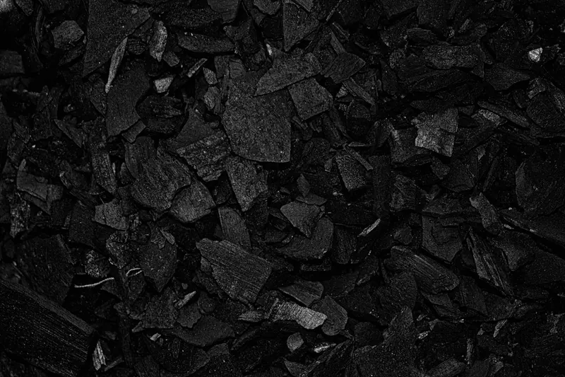 Detailed view of black charcoal pieces arranged in a pile for grilling or art use
