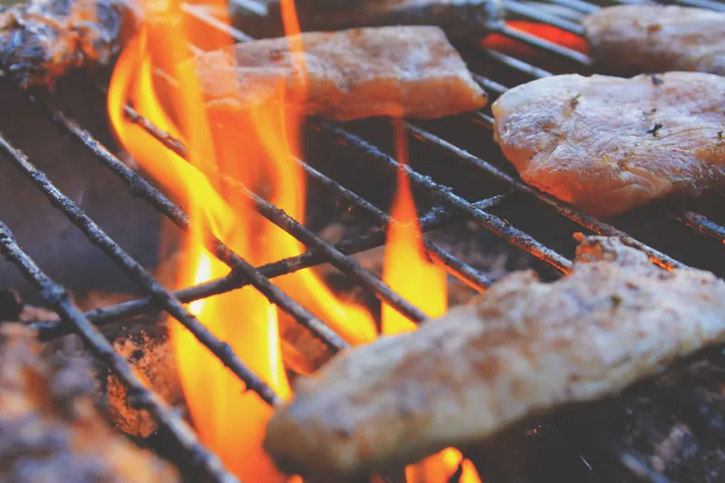 Close-up of grilling meat on open flames showcasing the BBQ experience