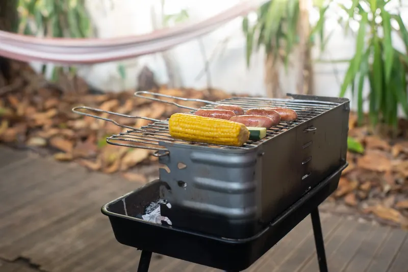 Grilled sausages and corn on an outdoor barbecue in a rustic setting