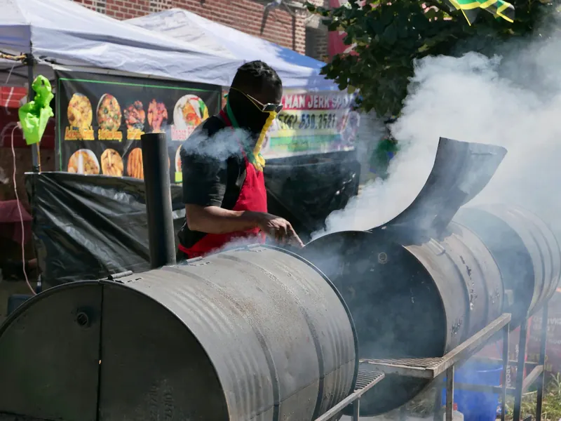 Person grilling on a BBQ smoker at a vibrant New York street food festival