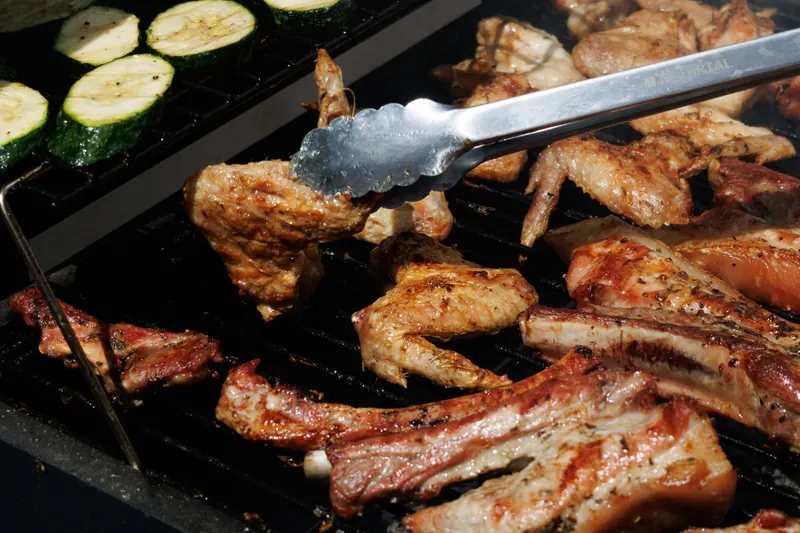 Juicy meat and zucchini being grilled on a barbecue under the summer sun