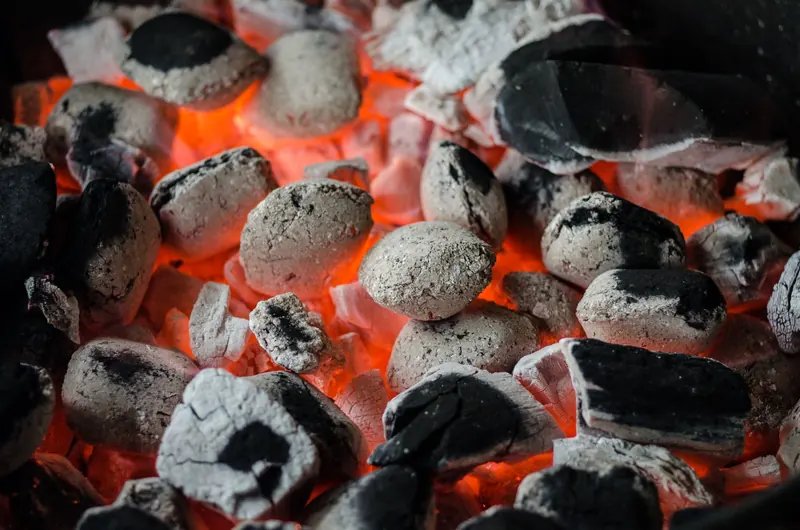 Close-up of glowing charcoal briquettes ready for outdoor barbecue grilling